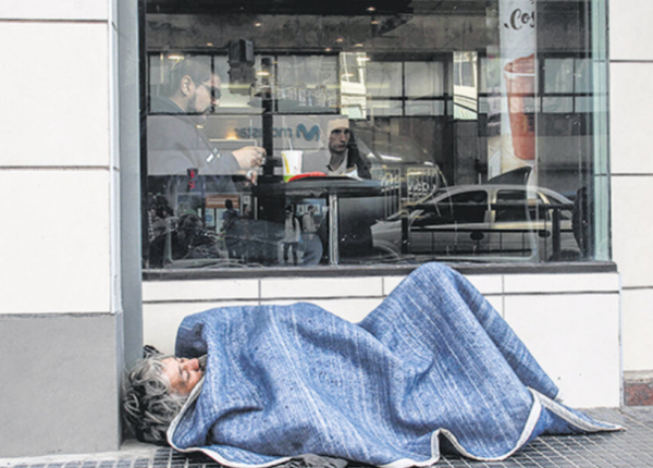 Persona en situación de calle en vereda de un bar